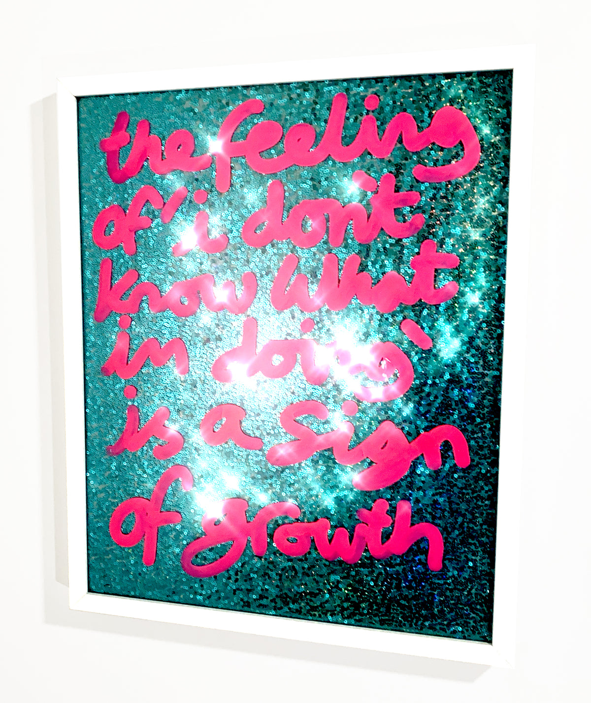 Sign of growth, neon pink ink over aqua green/blue sequins.