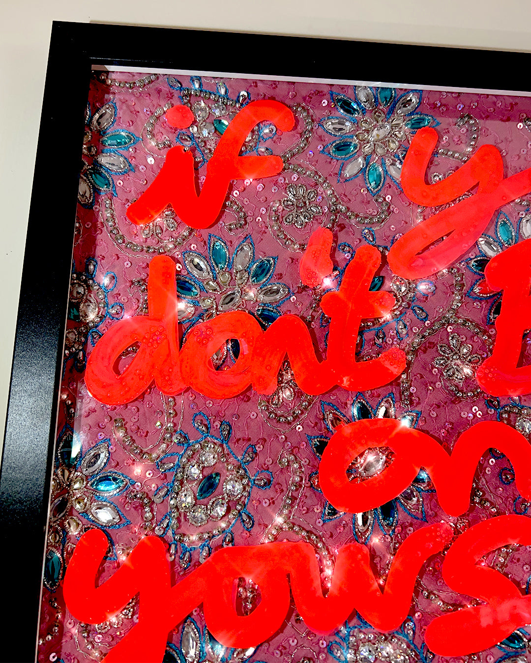 Bet on yourself. Fluorescent orange ink over pink, blue and silver bejewelled fabric.